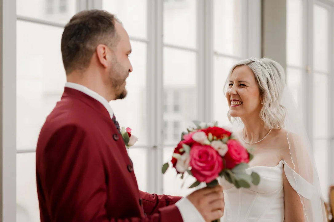 Braut und Bräutigam lachen gemeinsam bei ihrer romantischen Hochzeit im Schloss Wolfsberg