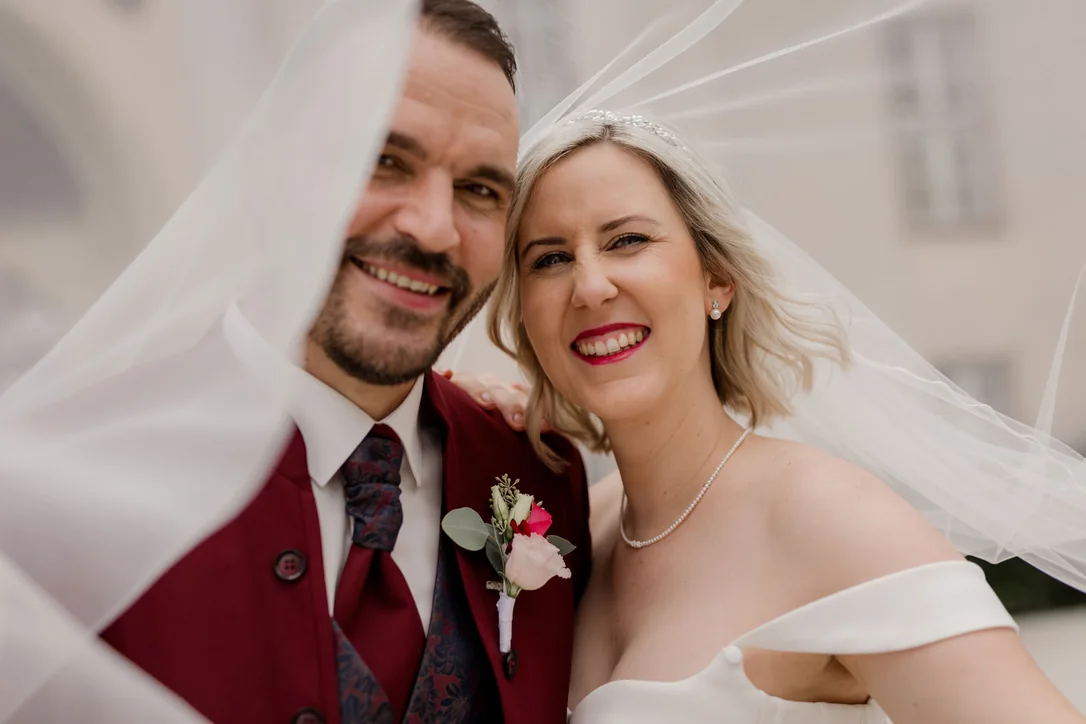 Lachendes Brautpaar unter dem Schleier bei seiner familiären Hochzeit in Kärnten